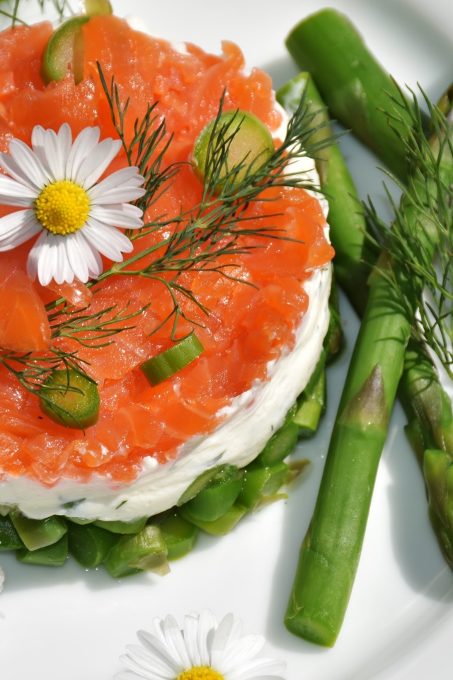 Салат с красной рыбой на тарелке со спаржей, укропом и цветами ромашки