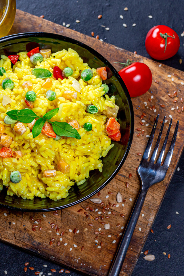 Rice with vegetables on a table with butter, herbs and tomatoes
