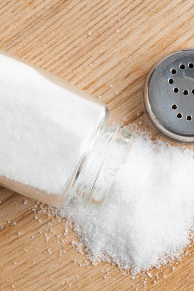 Соль рассыпана на деревянном столе 