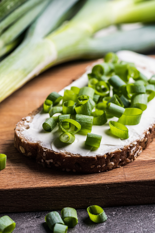 Бутерброд с маслом и зеленым луком на столе 