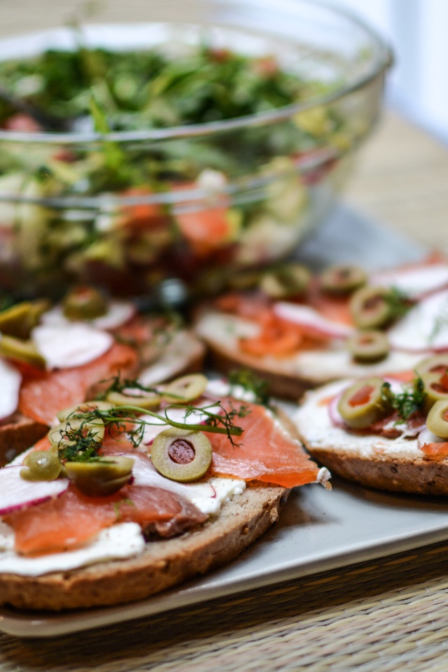 Бутерброды с маслом и красной рыбой на столе с салатом