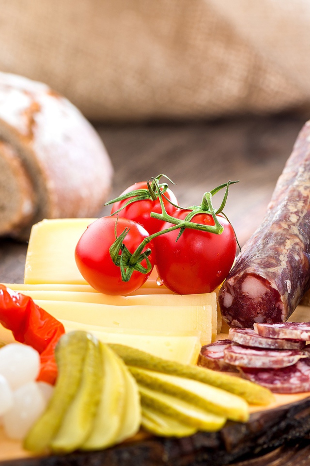 Колбаса на столе с огурцами, помидорами и перцем