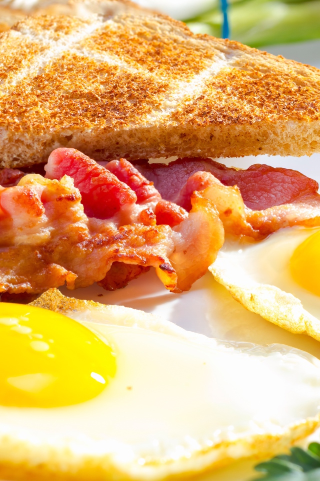 Яичница, бекон и гренки на завтрак на столе 