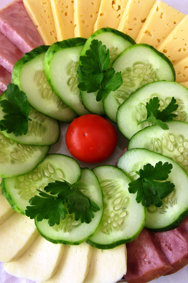 Сыр нарезанный, огурцы и ветчина на тарелке 