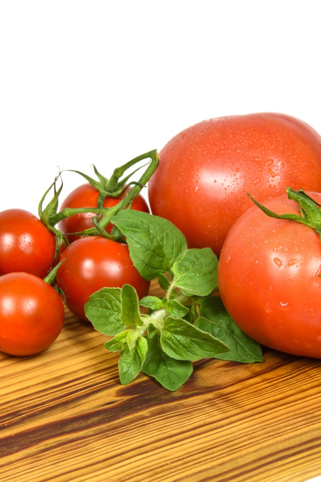 Маленькие и большие помидоры на деревянной доске 