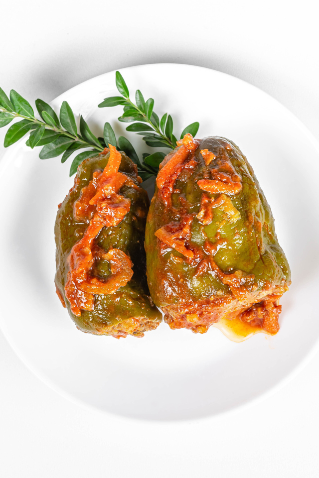 Фаршированный перец на белой тарелке со столовыми приборами