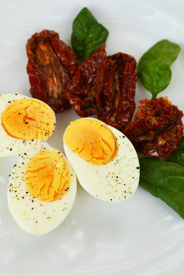 Вяленые помидоры на тарелке с базиликом и вареными яйцами