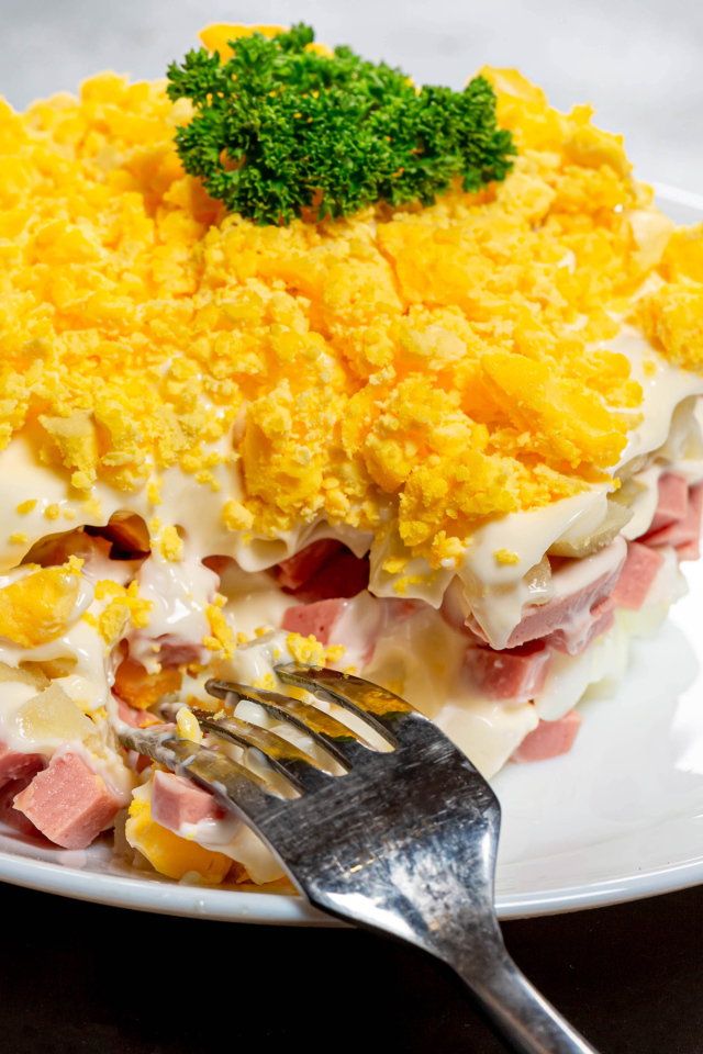 Вкусный салат на белой тарелке с вилкой