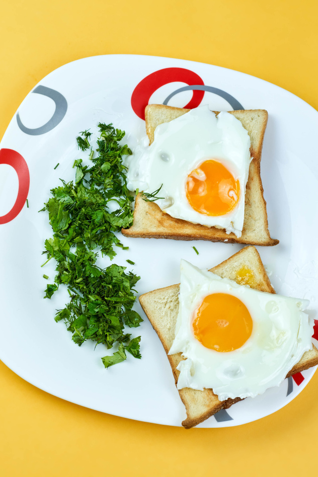 Тосты с яичницей на тарелке с зеленью петрушки 