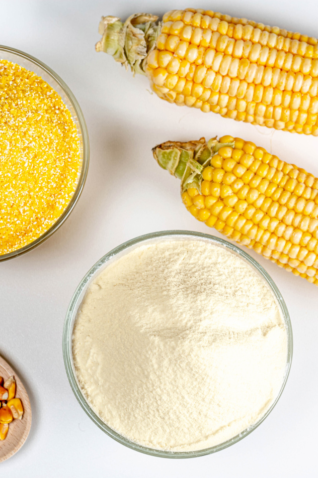 Два початка кукурузы на белом фоне с крупой и мукой 