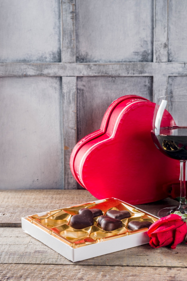 Два бокала вина, шоколадные конфеты и розы на столе для любимой 