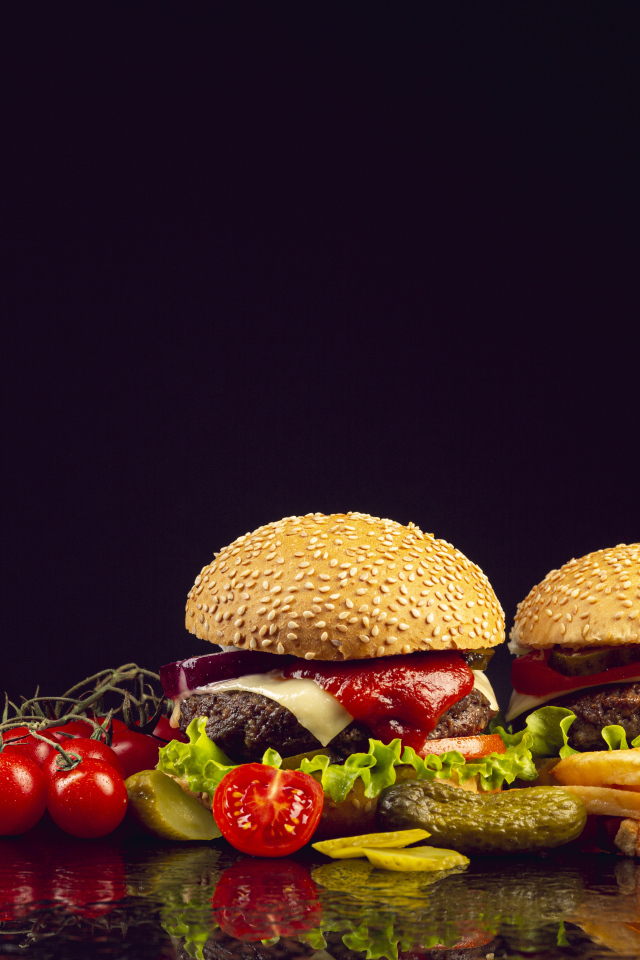 Два гамбургера на столе с ножом, овощами и кетчупом 