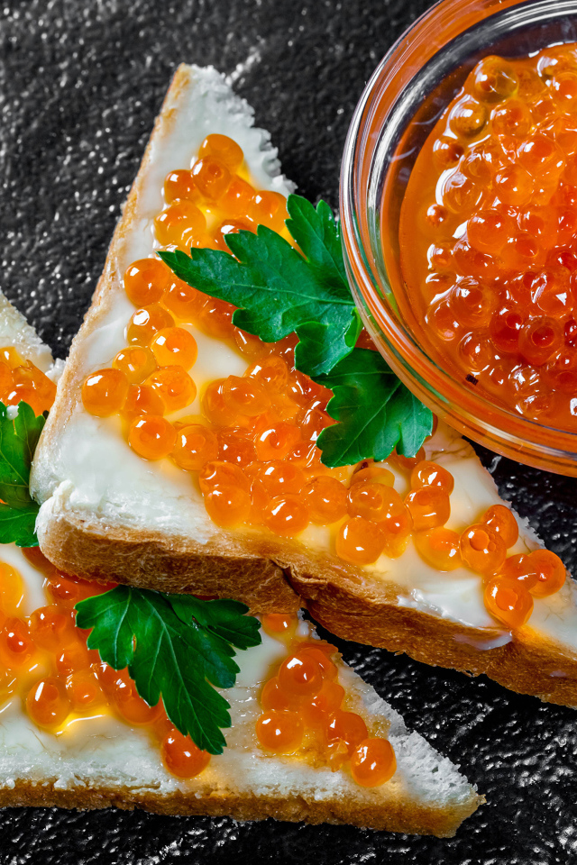Два бутерброда с красной икрой на столе