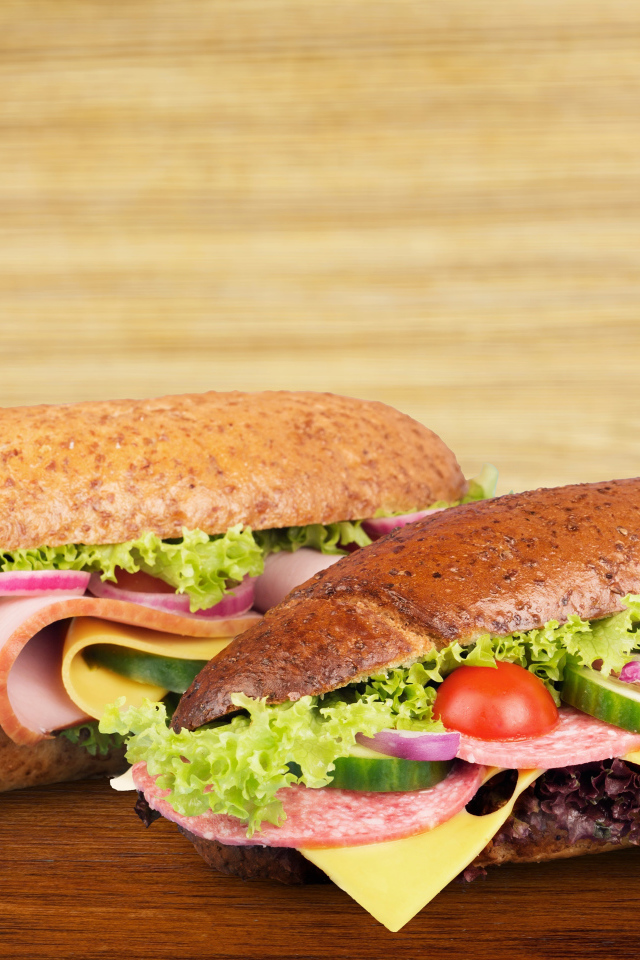 Два вкусных бутерброда с овощами и колбасой на столе 