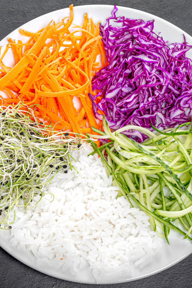 Овощи с рисом на большой  белой тарелке на сером столе 