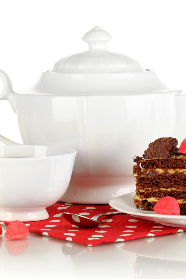 Белая чашка чая и чайник на столе с куском торта