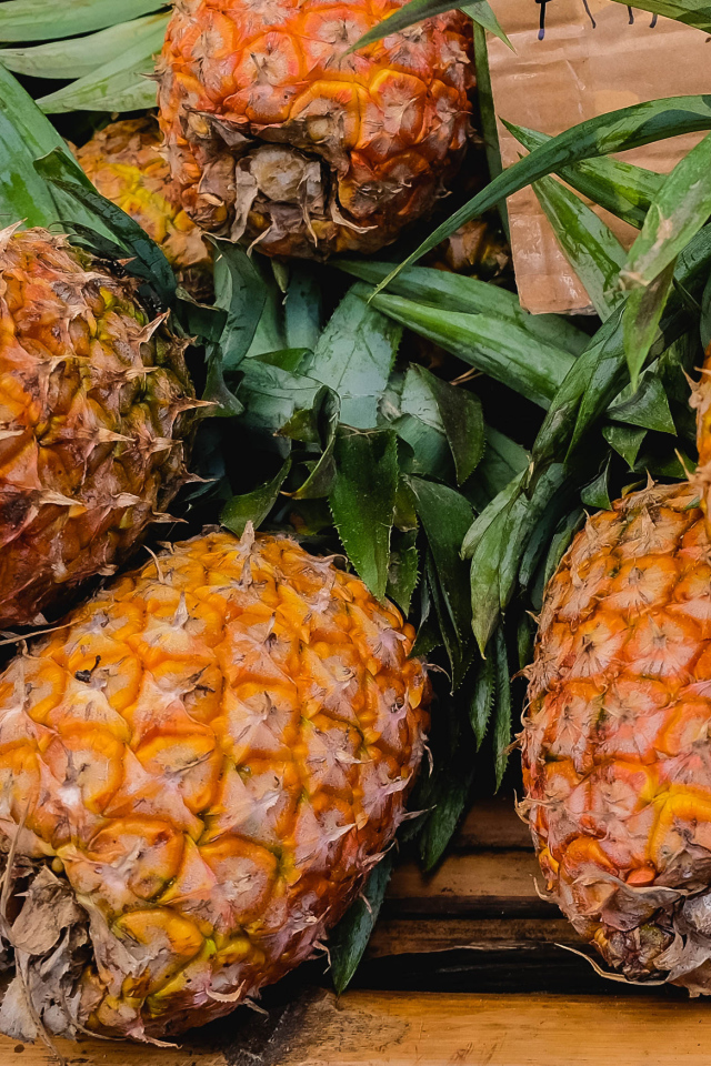 Много больших спелых ананасов на столе 