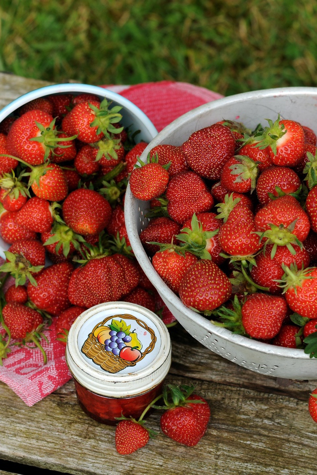 Много спелой ароматной клубники на столе с джемом 