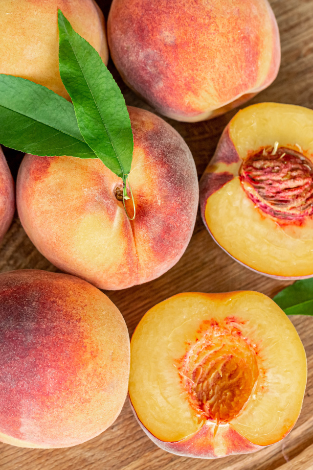 Appetizing fresh peaches on wooden board