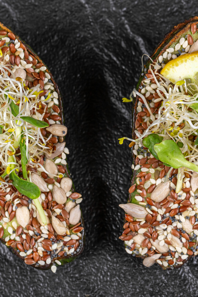 Половинки авокадо с проросшими зернами на столе