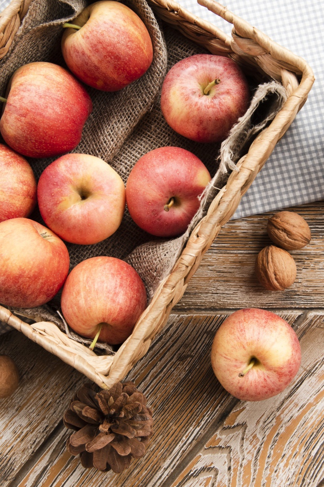 Корзина с яблоками на столе с сосновыми шишками