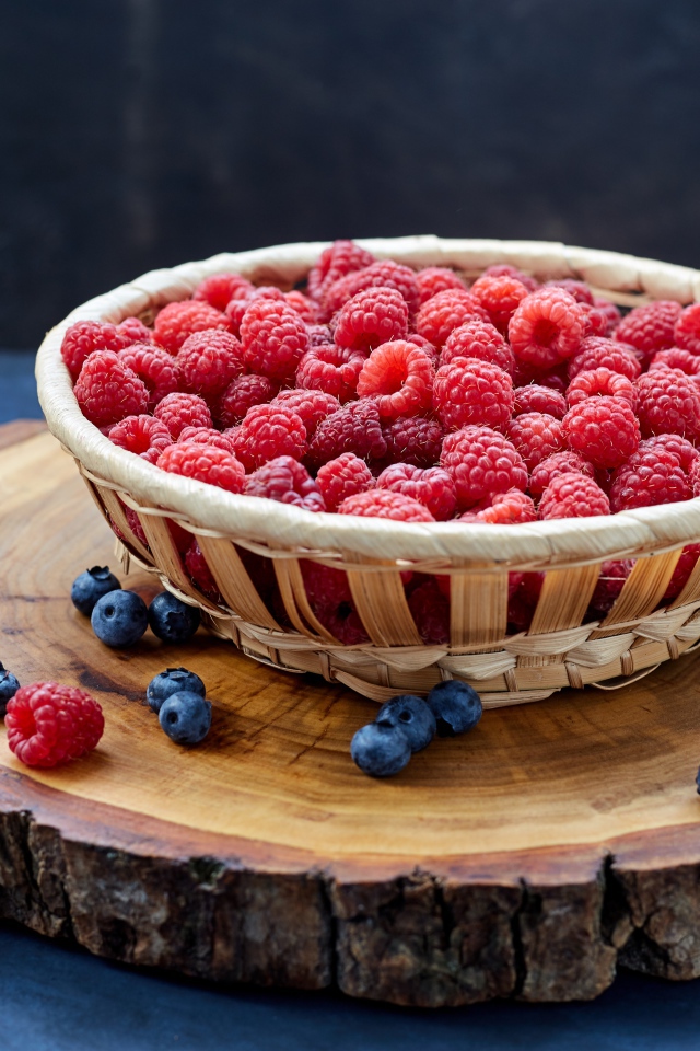 Корзинка с малиной на столе с ягодами черники