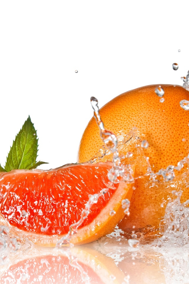 Большой спелый апельсин в брызгах воды на белом фоне