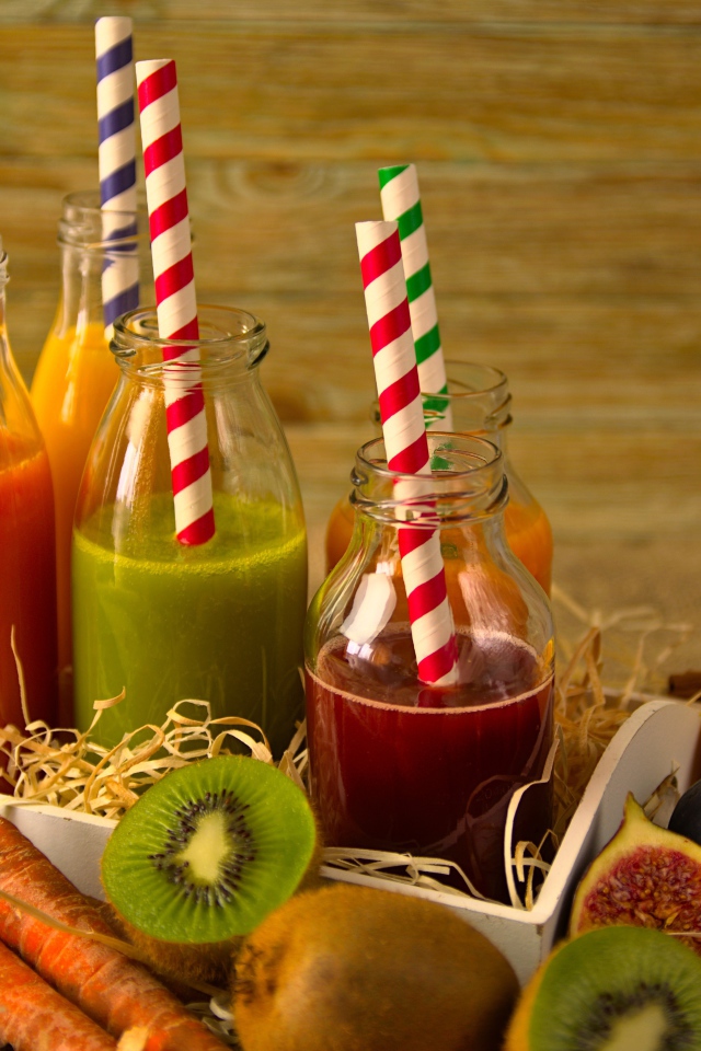 Бутылочки с соком на столе с фруктами 