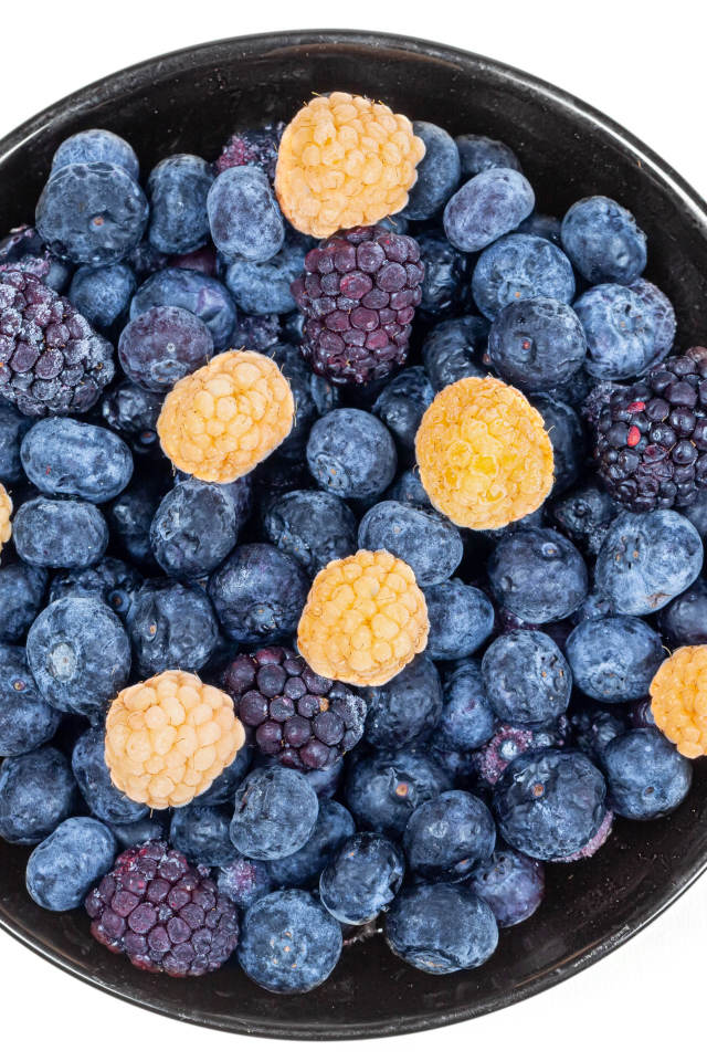 Миска с замороженными ягодами черники и ежевики на белом фоне