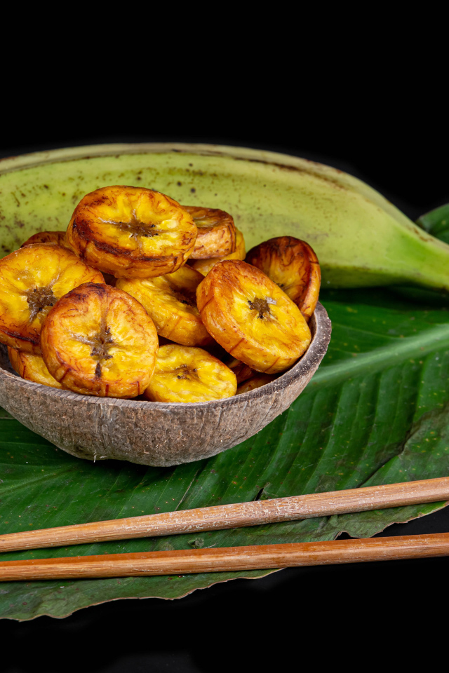 Сушеные бананы на столе с палочками и зеленым листом