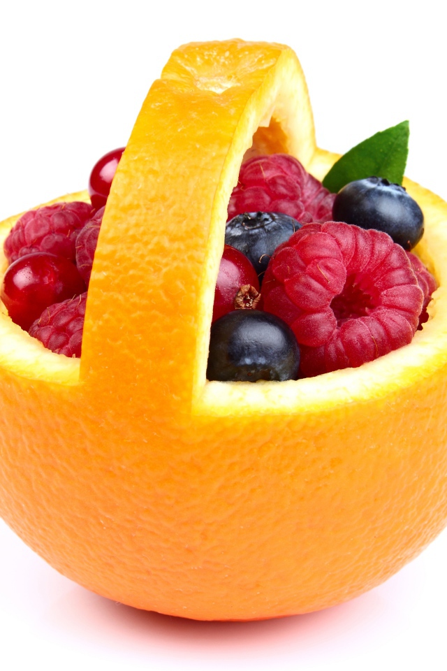 Свежие ягоды в кожуре апельсина на белом фоне