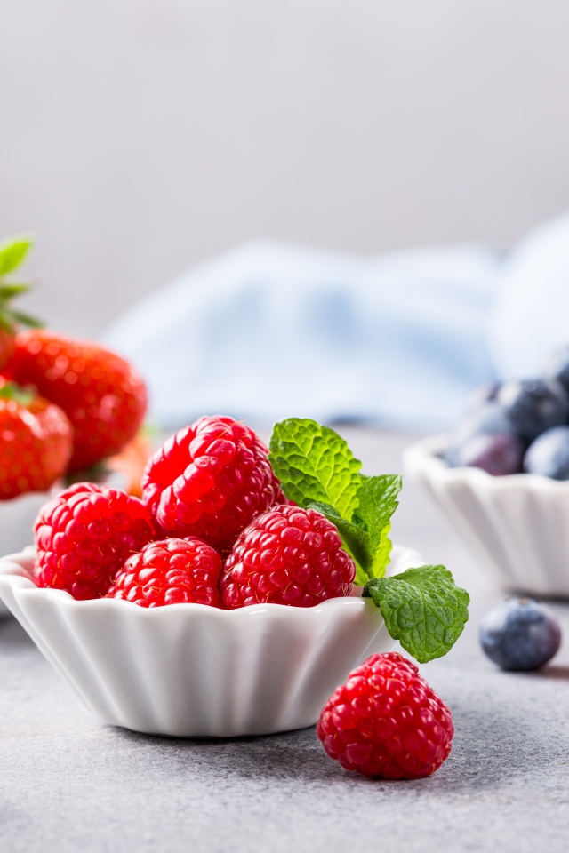 Свежие ягоды малины, клубники и черники на столе