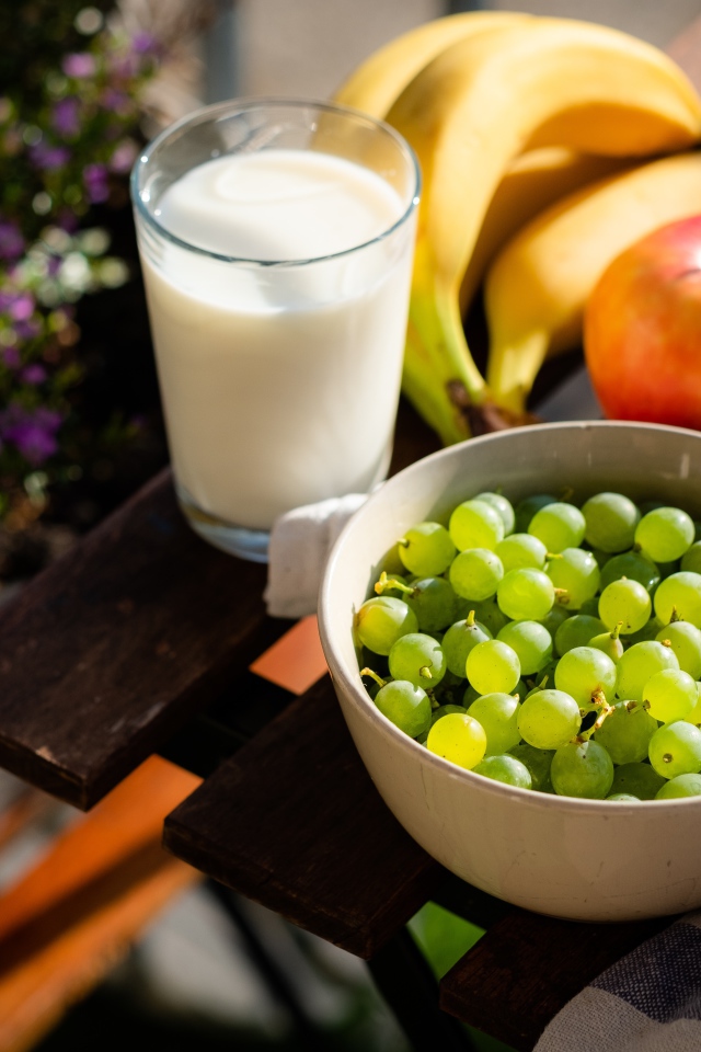 Зеленый виноград на столе с бананами, яблоками и молоком