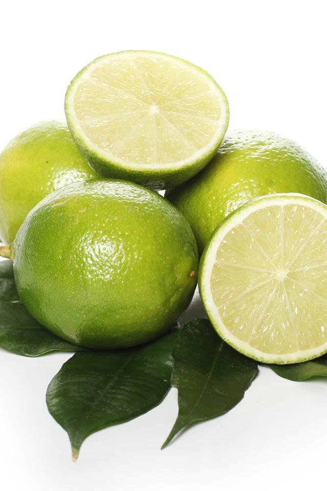 Зеленые лаймы с листьями на белом фоне