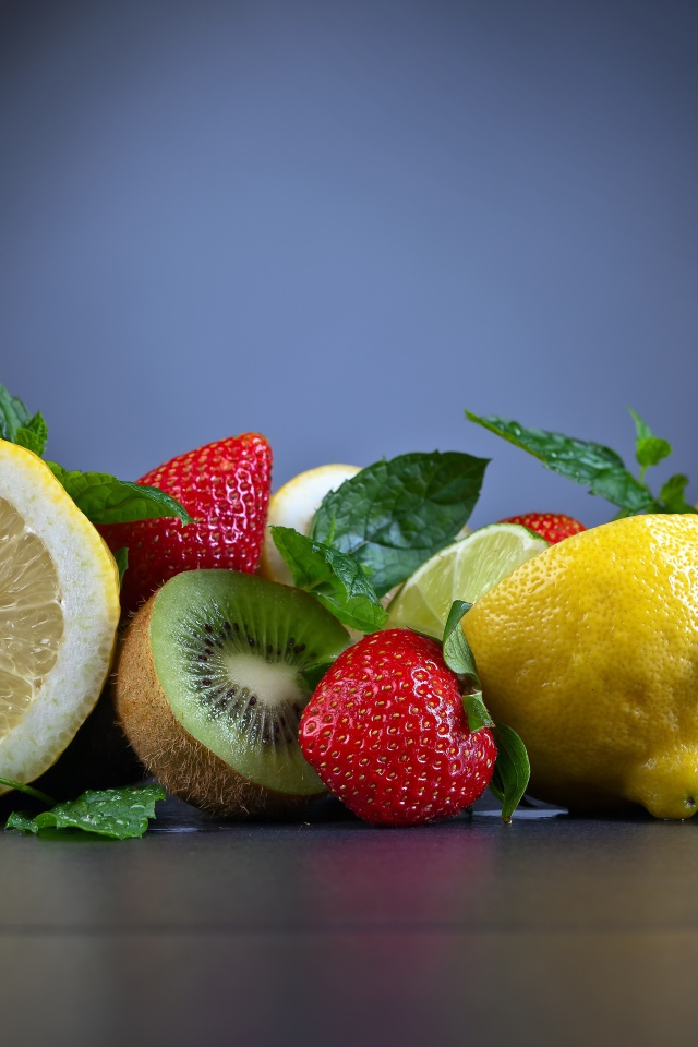 Лимоны на столе с киви и ягодами клубники 