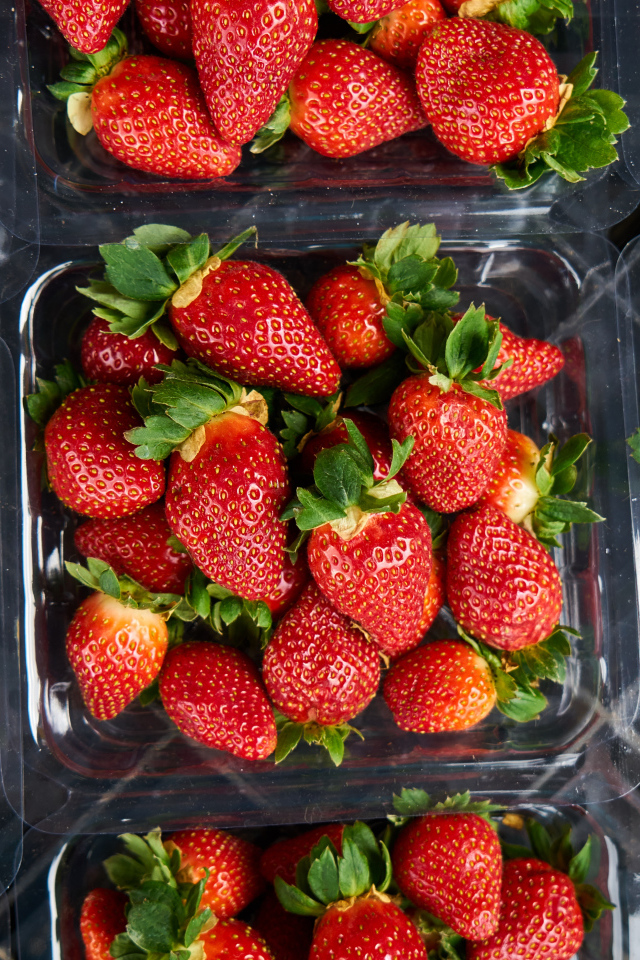 Много контейнеров со спелой сочной красной клубникой 