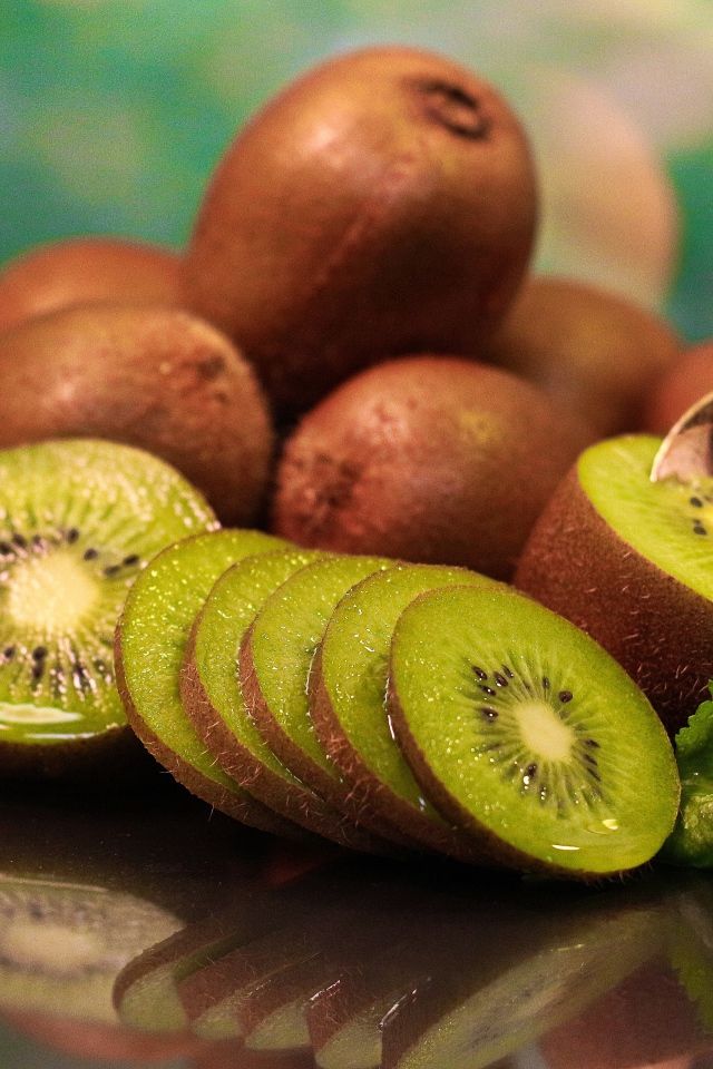 Много спелых плодов киви на столе с ложкой 