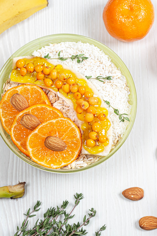 Мюсли с облепихой, бананом и апельсином на столе с фруктами