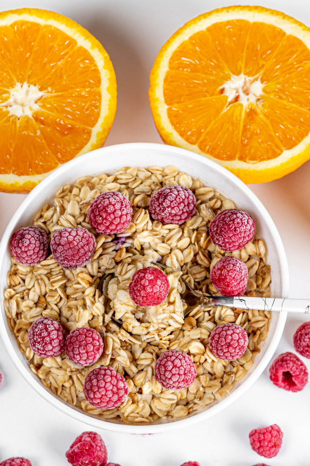 Овсяные хлопья с малиной на белом фоне с апельсинами