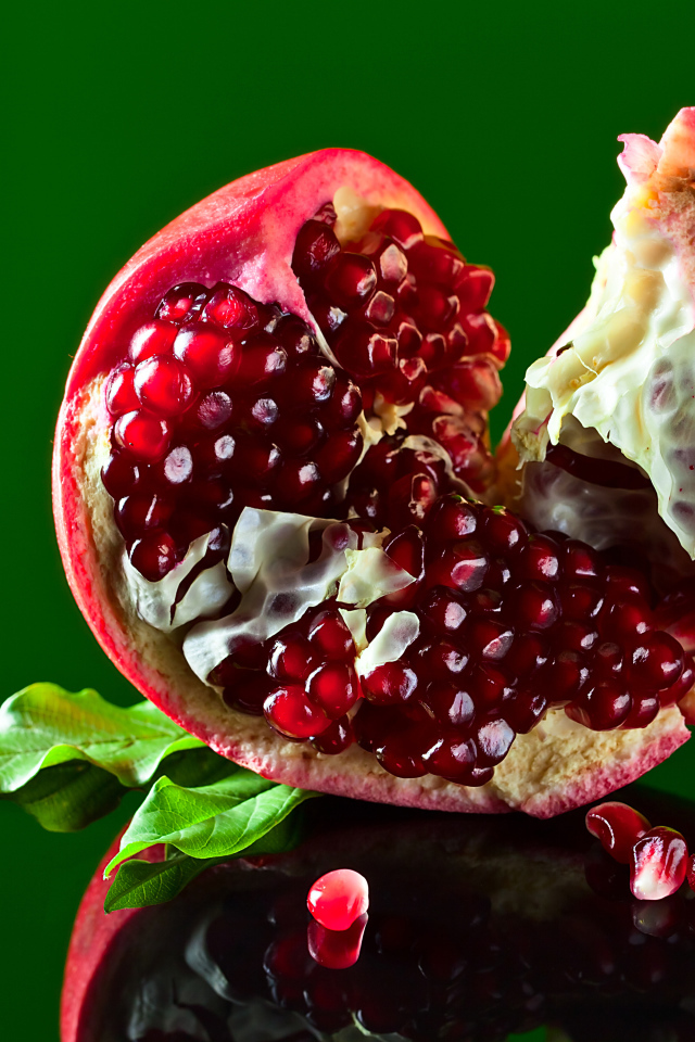 Очищенный гранат на зеленом фоне