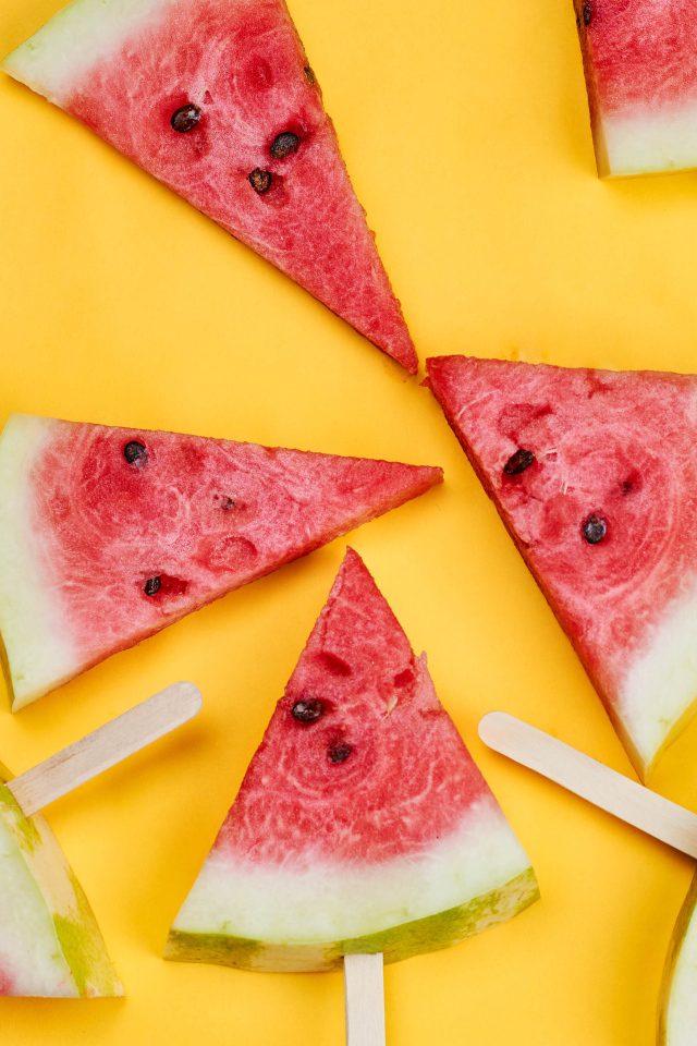 Кусочки арбуза на палочках на желтом фоне