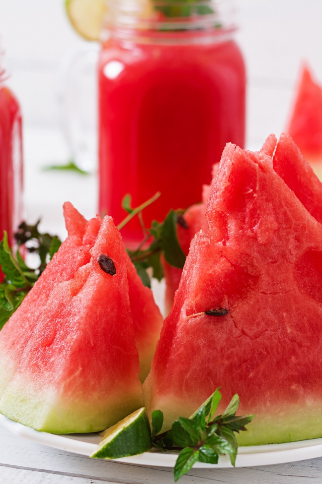 Куски арбуза с мятой на столе с соком 