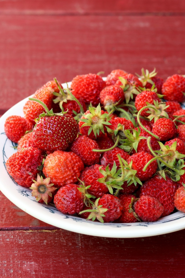 Тарелка со спелой домашней клубникой на столе