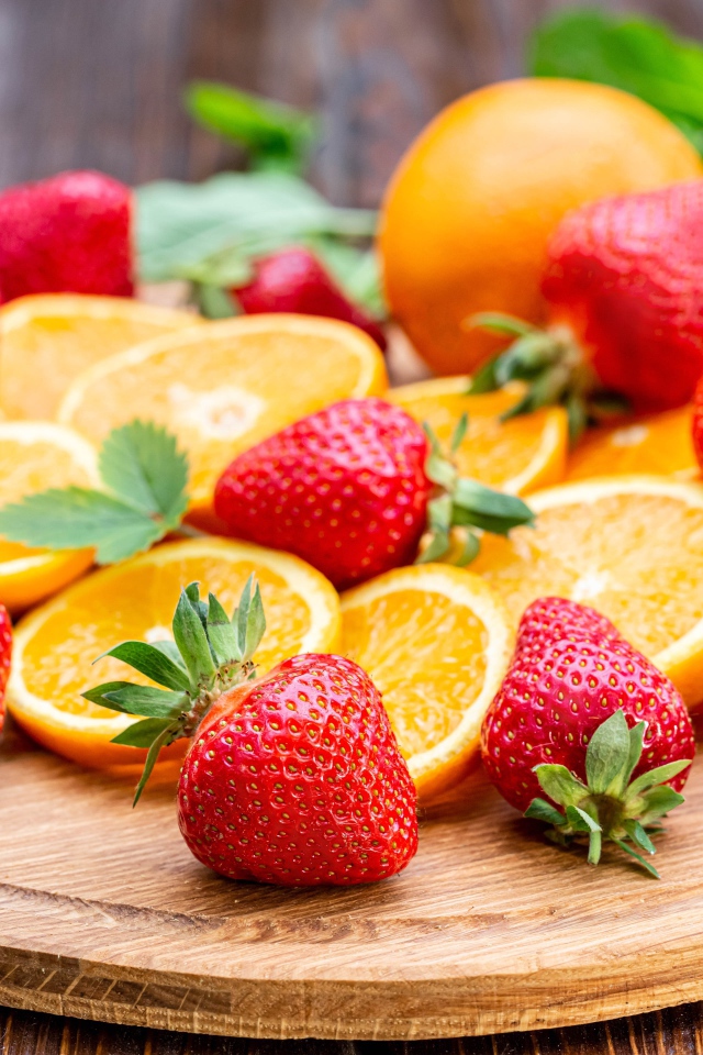 Красная свежая клубника на доске с кусочками апельсина