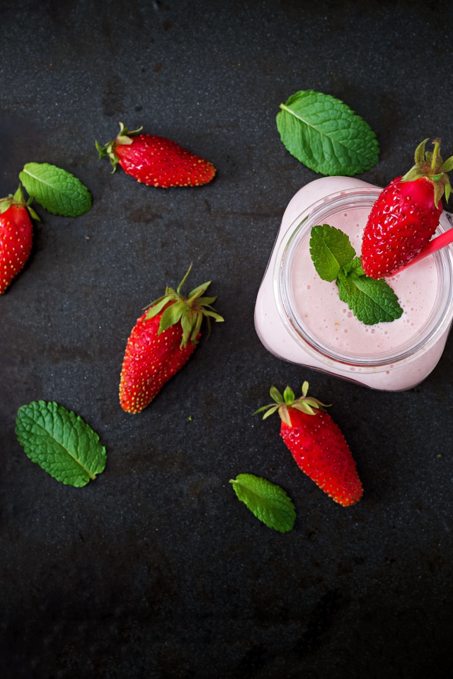 Красная клубника на черном столе с йогуртом