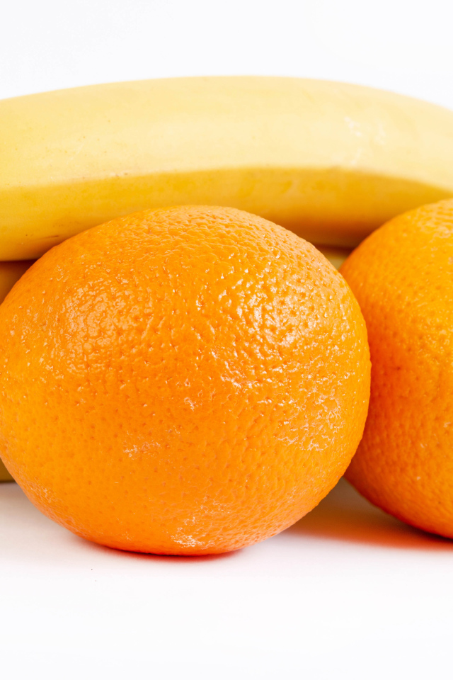 Спелые апельсины и бананы на белом фоне 