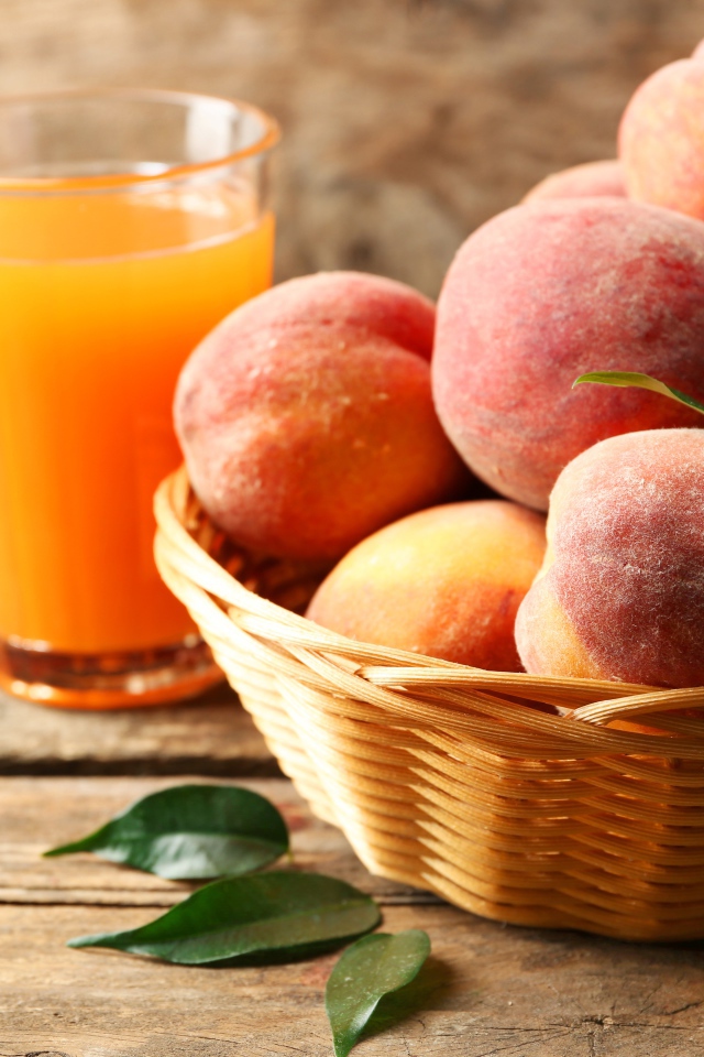 Спелые персики в корзине на столе с соком
