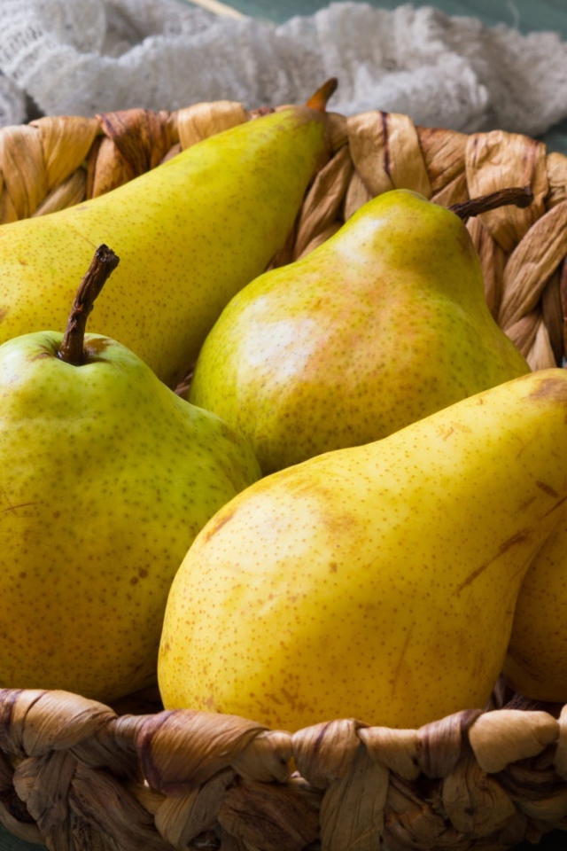 Спелые груши лежат в корзине на столе