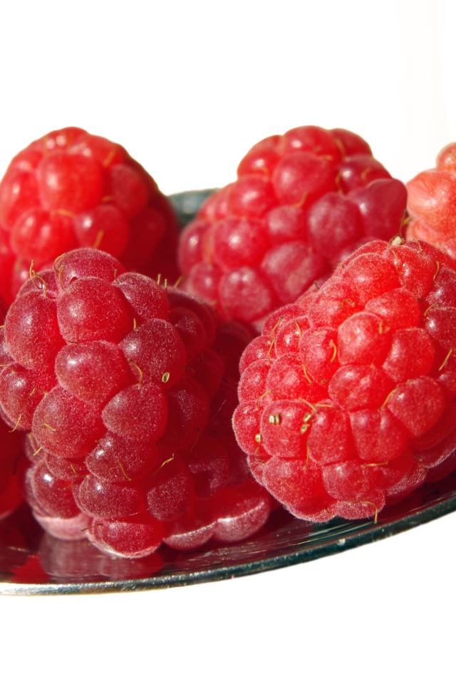 Спелая красная малина в ложке на белом фоне 