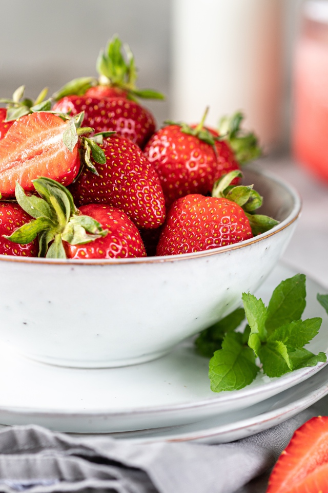 Спелая клубника с мятой на столе в белой тарелке 